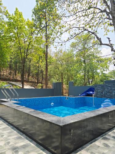 a hot tub in a patio with trees in the background at Forest Retreat Khalanga in Rāipur
