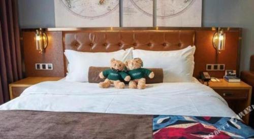 two teddy bears sitting on top of a bed at James Joyce Coffetel·Beijing Yizhuang Development Zone Dazu Square Tongji Road in Beijing