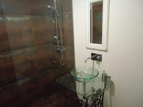 a bathroom with a glass sink and a shower at A Casa Estrelícia-Dourada Garcês in São Vicente