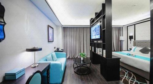 a hotel room with a blue couch and a bed at Xana Hotelle Jinan Wuanfu Interchange Huafu International Square in Jinan