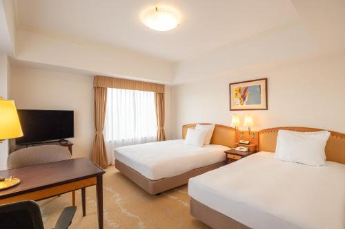 a hotel room with two beds and a desk at ANA Crowne Plaza Toyama by IHG in Toyama