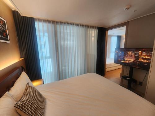a bedroom with a bed and a flat screen tv at Elbon the stay with A1 in Busan