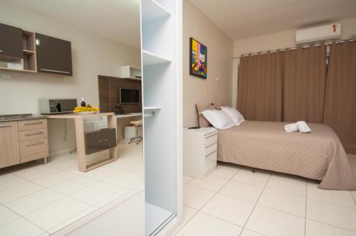 a bedroom with a bed and a desk and a kitchen at Flat Beira Rio in Ribeira