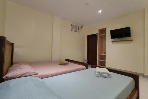 a bedroom with two beds and a tv on the wall at Elicon Suites Resort Bohol near City Center in Tagbilaran City