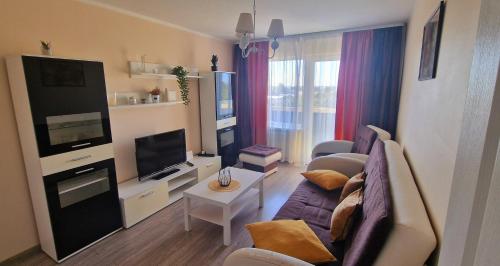 a living room with a couch and a tv at Saules 116 in Ventspils