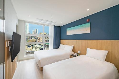 a hotel room with two beds and a window at Sokcho Mari Vista Hotel in Sokcho
