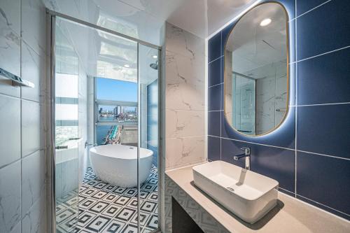 a bathroom with a tub and a sink and a mirror at Sokcho Mari Vista Hotel in Sokcho