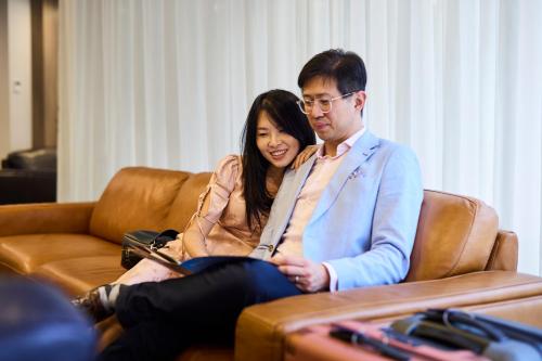 a man and a woman sitting on a couch at Brady Apartment Hotel Hardware Lane in Melbourne