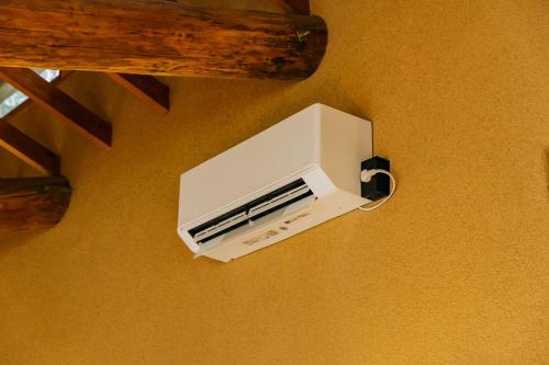 a white air conditioner is hanging on a wall at COCO VILLA 長瀞-Sauna- in Nagatoro