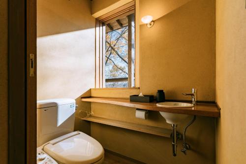 a bathroom with a toilet and a sink and a window at COCO VILLA 長瀞-Sauna- in Nagatoro
