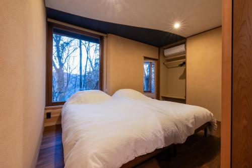 a bedroom with a bed and a large window at COCO VILLA 長瀞-Sauna- in Nagatoro