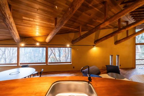 a room with a table and chairs and wooden ceilings at COCO VILLA 長瀞-Sauna- in Nagatoro