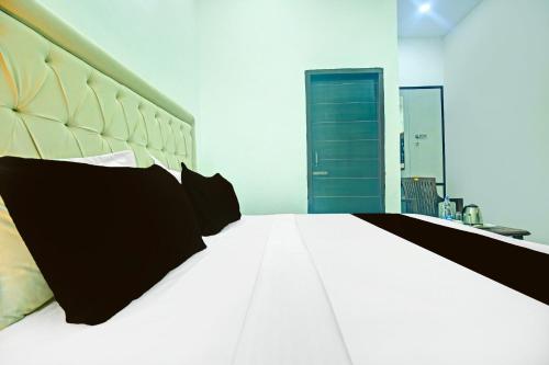 a bedroom with a large white bed with black pillows at Super Hotel O Sector 52 Chandigarh Formerly Hotel Muskan in Chandīgarh