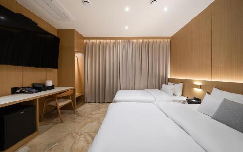 a hotel room with two beds and a desk at Incheon BrownDot Hotel Guwol in Incheon