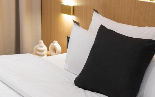 a bed with a black pillow and white pillows at Incheon BrownDot Hotel Guwol in Incheon