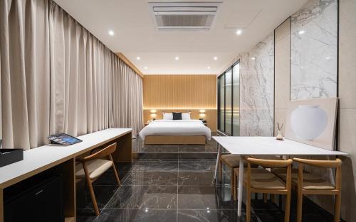 a hotel room with a bed and tables and chairs at Incheon BrownDot Hotel Guwol in Incheon