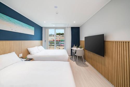 a hotel room with two beds and a flat screen tv at Sokcho Mari Vista Hotel in Sokcho