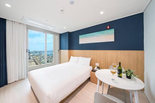 a hotel room with a bed and a table with wine glasses at Sokcho Mari Vista Hotel in Sokcho