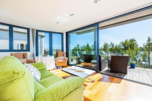 a living room with a green couch and large windows at Llevant in Portocolom