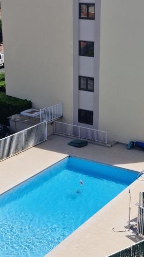 une grande piscine bleue à côté d'un immeuble dans l'établissement Grand Plongeon de la Piscine de notre Studio, à Canet