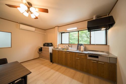 a kitchen with wooden cabinets and a ceiling fan at Takachiho Sanso Amaterasu Kagura in Takachiho