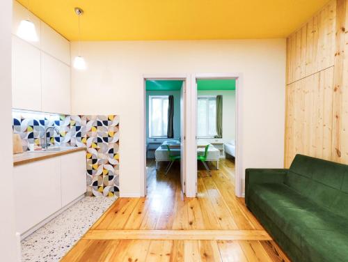 a living room with a green couch and a kitchen at Guest House Bolnisi - Duplex apartment in Bolnisi