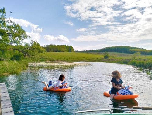 two girls riding on tubes in a river at Agroturystyka Camilleri in Młynary