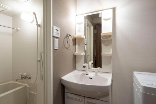 a white bathroom with a sink and a mirror at Locanda shin-Osaka in Osaka