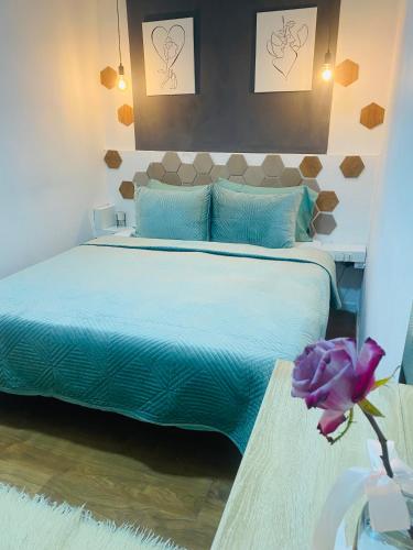 a bedroom with a bed with blue sheets and a purple flower at Romeo apt with private garden in Korçë