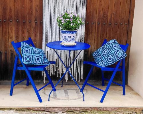 two blue chairs and a table with a vase of flowers at La casa del Herrero in Villanueva de Viver