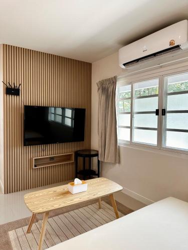 a living room with a tv and a wooden coffee table at Indigo Studio 2 mins from SRT Wat Samien Nari in Bangkok