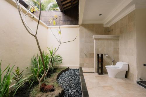 a bathroom with a toilet and a tree in it at Ombak Sunset in Gili Trawangan