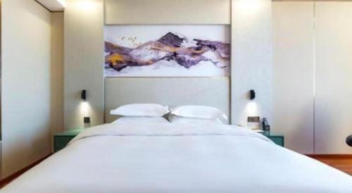 a bedroom with a large white bed with two pillows at Junyu Grand Hotel Qinhuangdao in Qinhuangdao