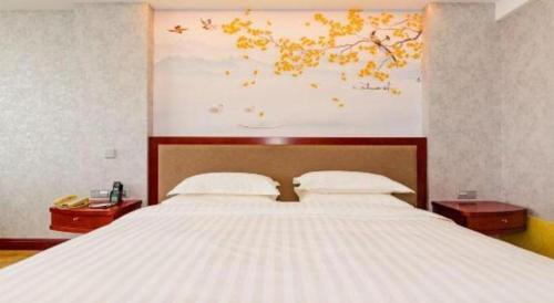 a bedroom with a large white bed with two night stands at Junyu Grand Hotel Qinhuangdao in Qinhuangdao