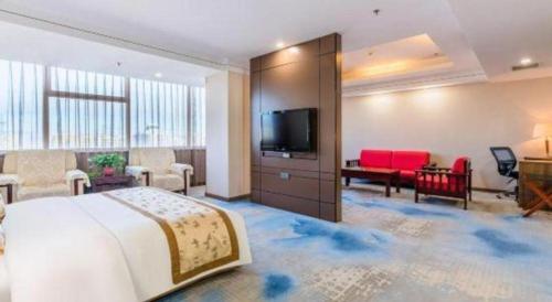 a hotel room with a bed and a flat screen tv at Junyu Grand Hotel Qinhuangdao in Qinhuangdao