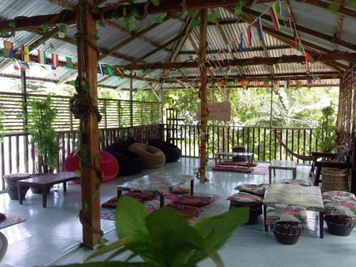 un gran pabellón con mesas, sillas y banderas en El Nido mama hostel, en El Nido