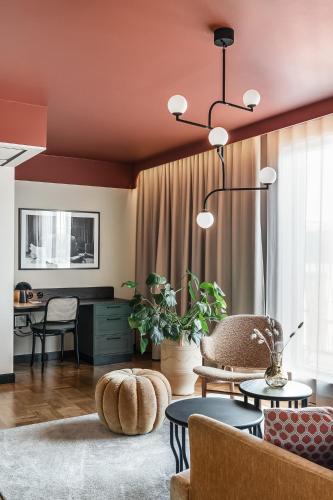 a living room with orange walls and tables and chairs at Hotel Fratelli in Karlstad