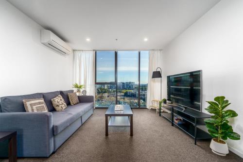 a living room with a blue couch and a tv at Luxury Living and Pool Views in the Heart of Woden - Hosted by Canstay in Phillip