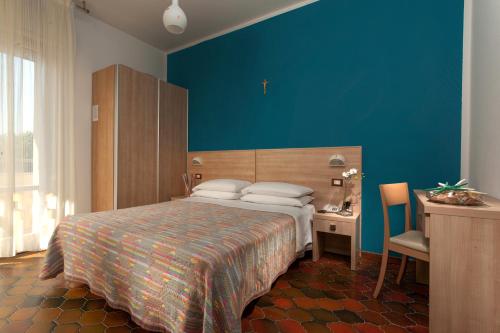 チェゼナーティコにあるHotel Gattuccioの青い壁のベッドルーム1室(ベッド1台付)