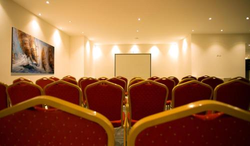 a conference room with red chairs and a screen at GHS Hotel in Brazzaville