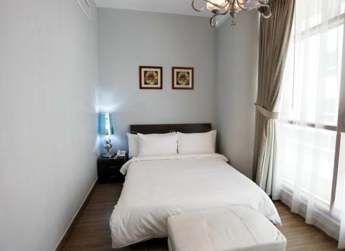 a bedroom with a white bed and a window at Al Manzil Hotel Bahrain in Juffair