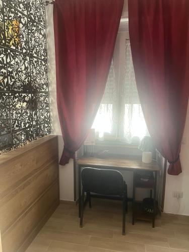a table with a chair and a window with curtains at Casetta 2 in Terracina