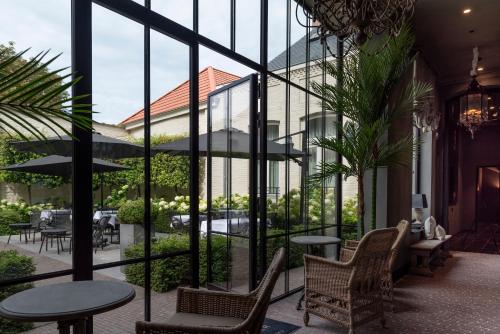 a patio with tables and chairs and windows at Cobergher Hotel in Kortrijk