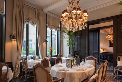 a dining room with tables and chairs and a chandelier at Cobergher Hotel in Kortrijk