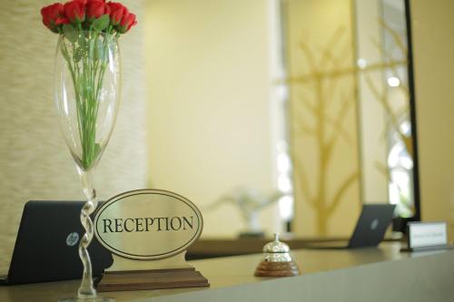 a vase with red flowers on a table with a mirror at GHS Hotel in Brazzaville