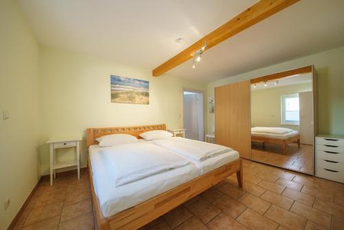 a bedroom with a large white bed and a mirror at Ferienwohnungen Wollenberg in Ahlbeck