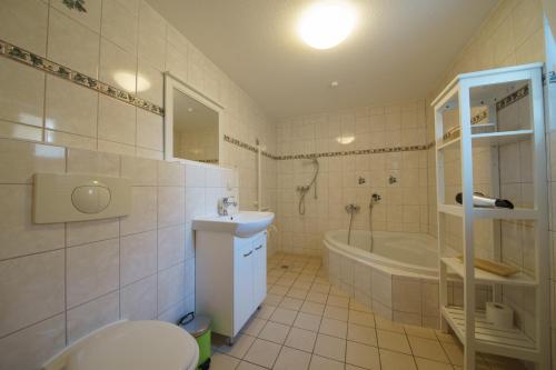 a bathroom with a toilet and a tub and a sink at Ferienwohnungen Wollenberg in Ahlbeck