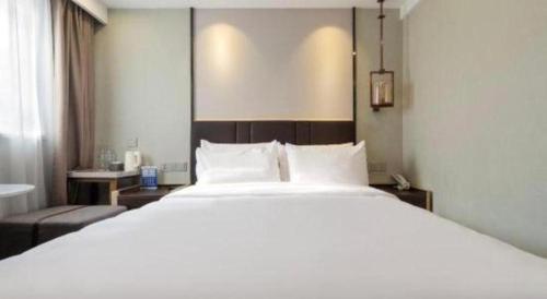 a large white bed in a hotel room at Magnotel Shanghai Maglev Station in Shanghai