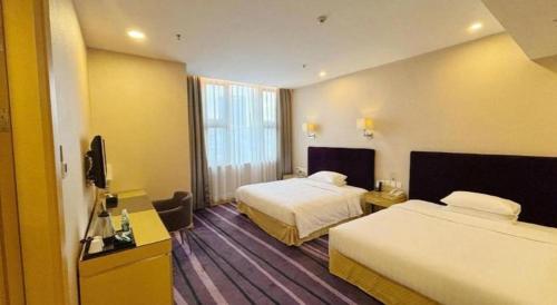 a hotel room with two beds and a flat screen tv at The Bauhinia in Shenzhen