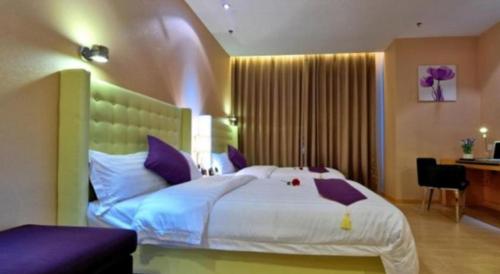 a bedroom with a large white bed with purple pillows at The Bauhinia in Shenzhen